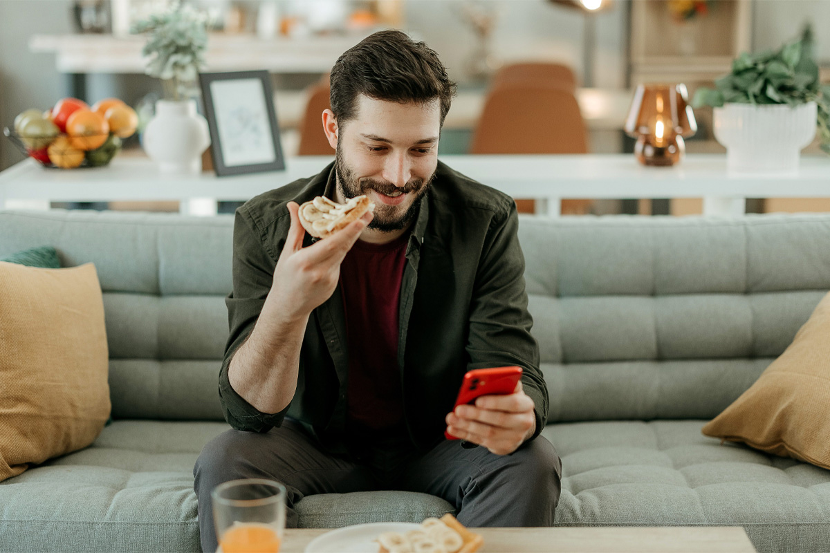 hombre comiendo mientras ve el celular