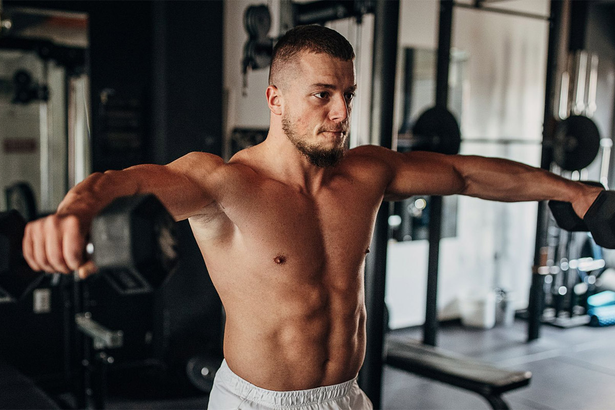 hombre haciendo elevaciones laterales con mancuernas para lograr crecimiento muscular