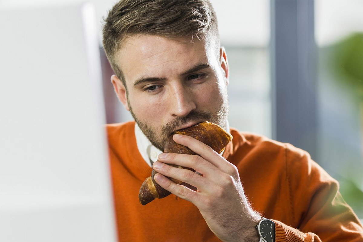 hombre comiendo frente a su computadora