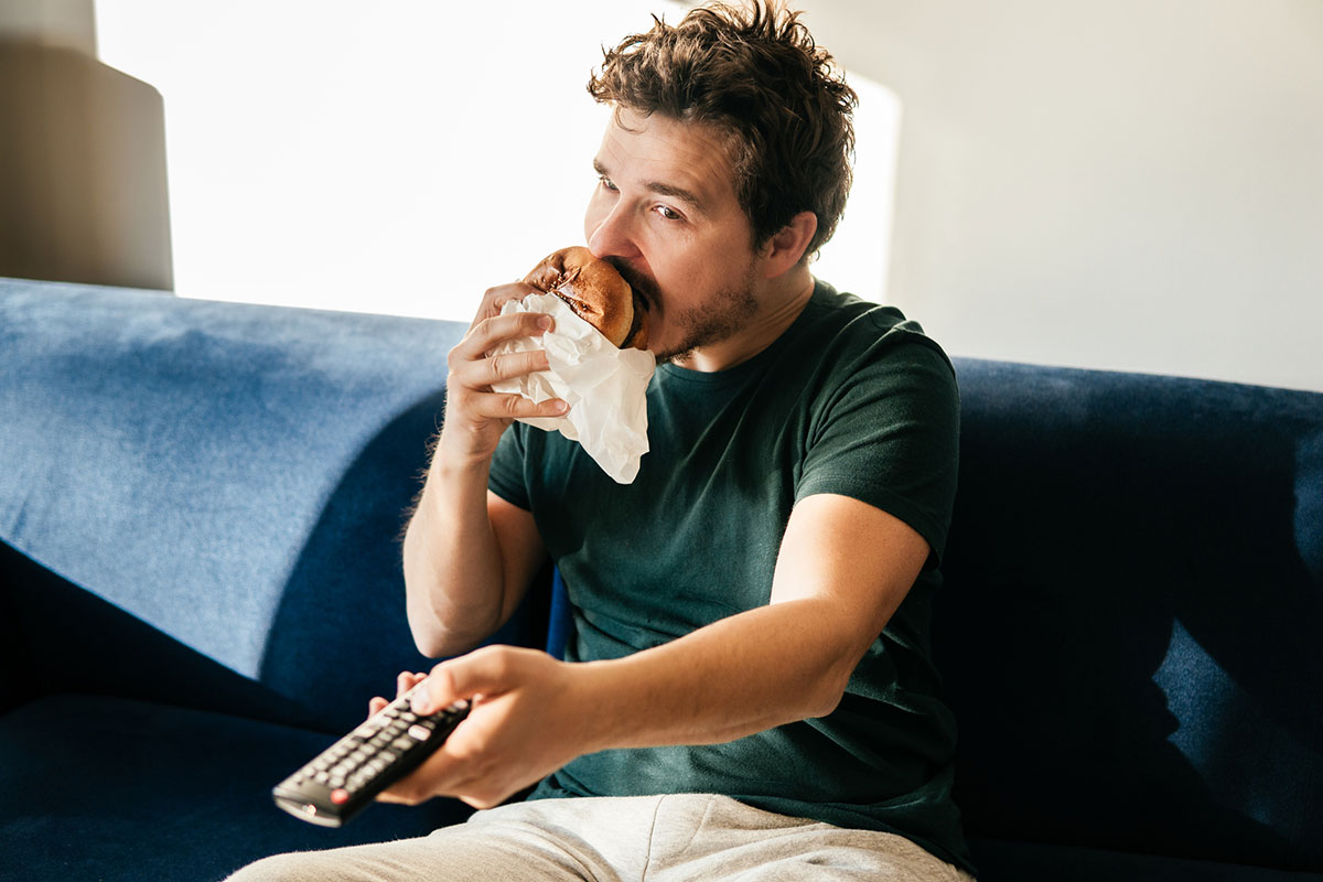 hombre comiendo frente a un televisor