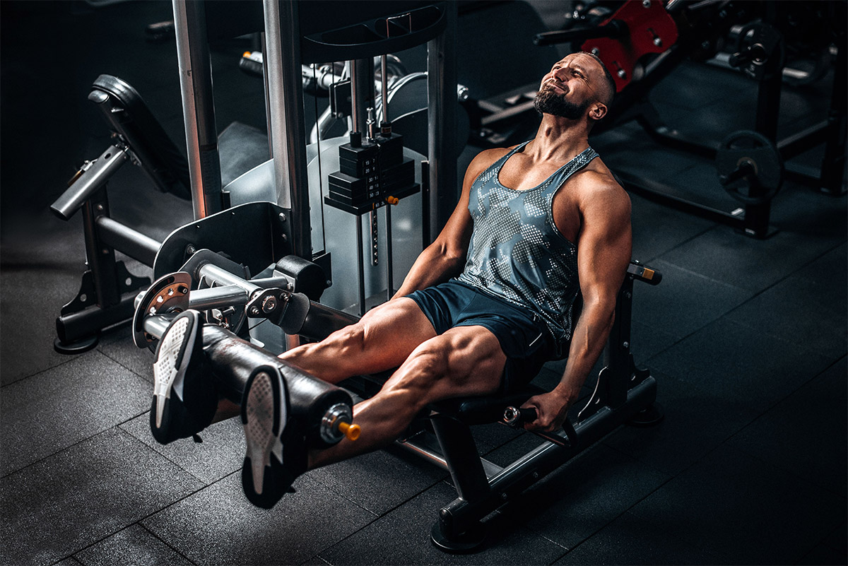 hombre haciendo extensión de piernas en máquina