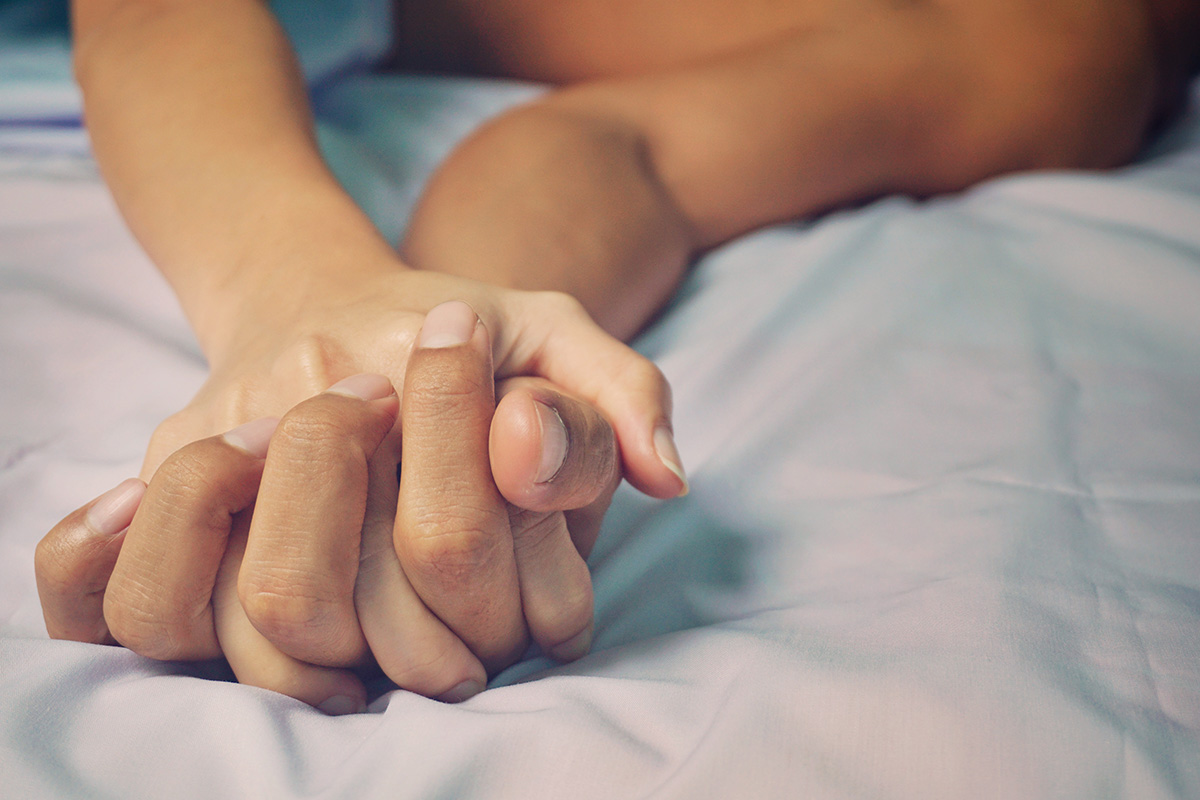 hombre y mujer tomados de la mano en la cama