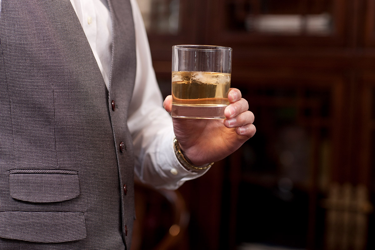 hombre sosteniendo un vaso de whisky