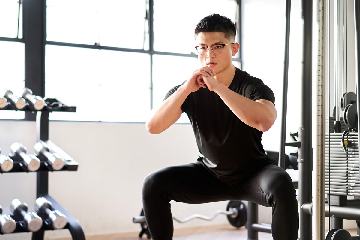 hombre haciendo sentadilla kang en el gimnasio