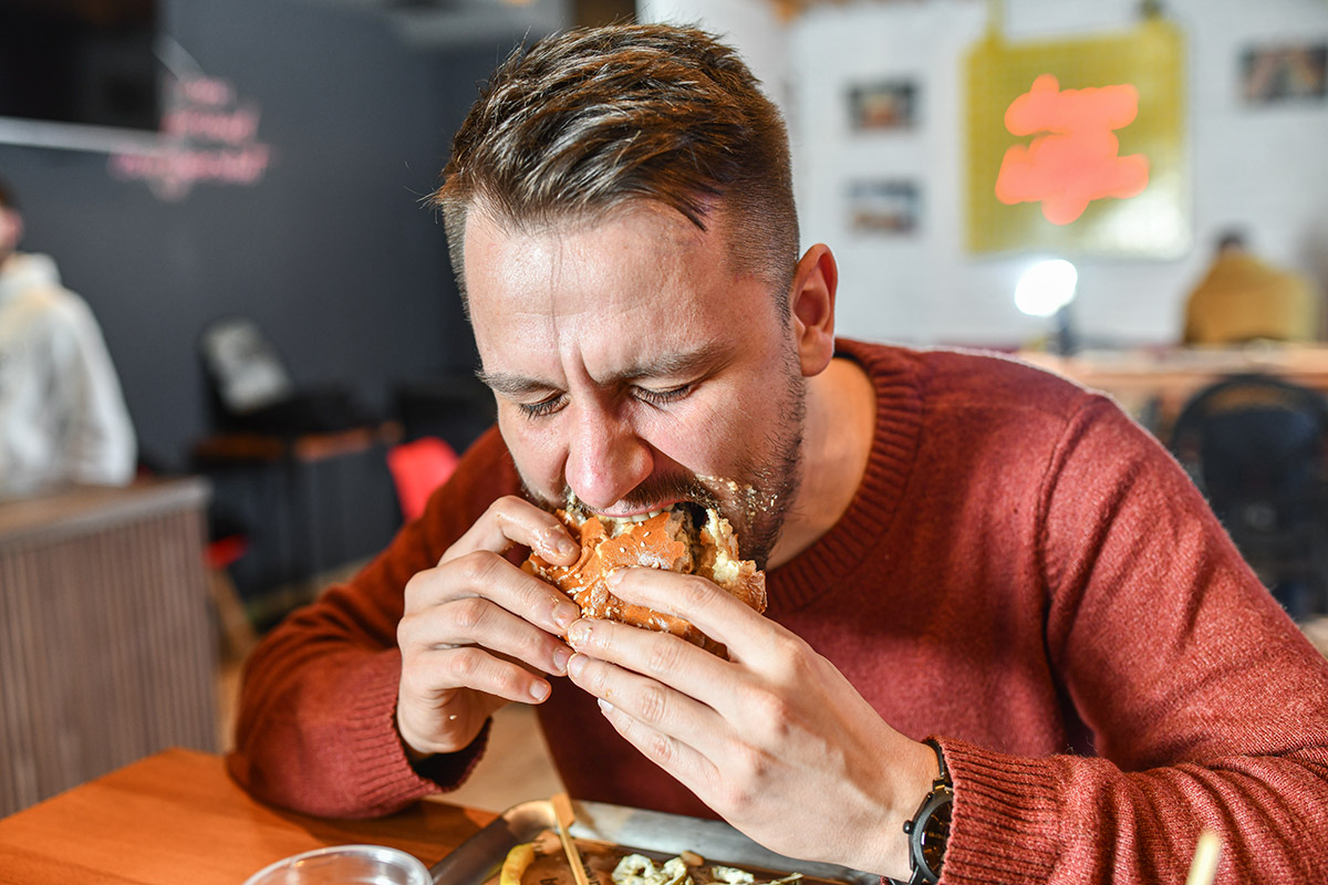 hombre dándole una mordida a una hamburguesa